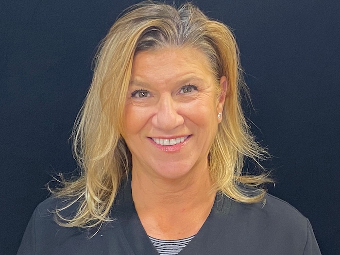 A woman with short hair, smiling at the camera, posing for a professional headshot.