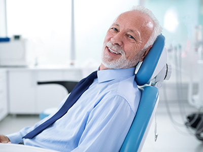 A man in a dental chair, smiling and looking directly at the camera.