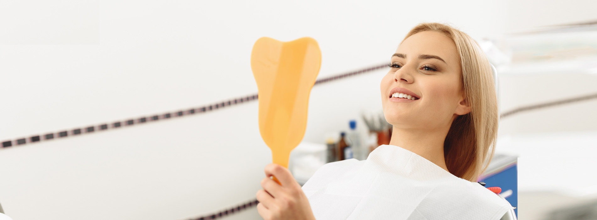 A person holding a toothbrush with a smiling expression, likely in a dental or oral care setting.