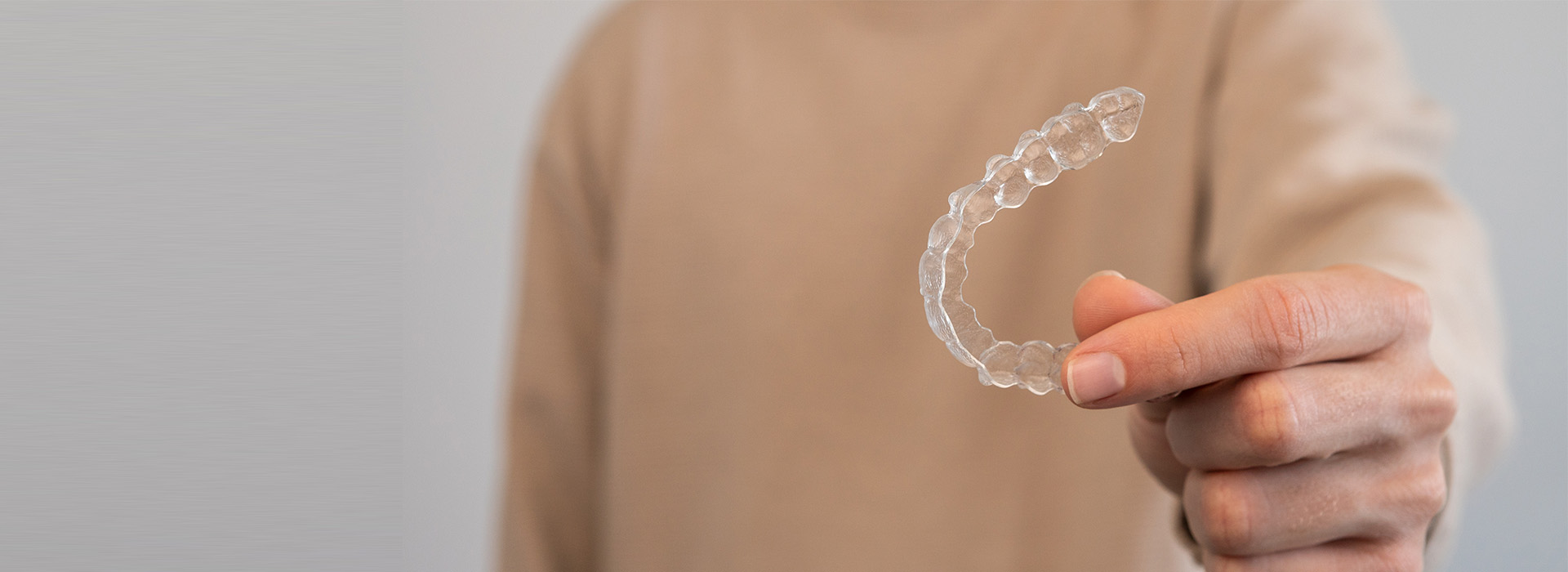 An individual s hand holding a transparent soap bubble, with the background blurred.