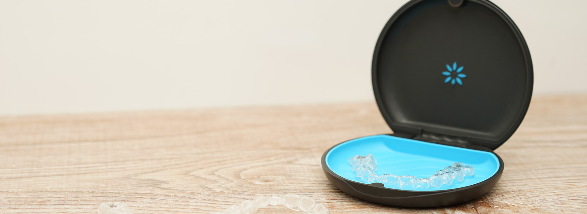 An image of a smart home device, which is a cylindrical object with a blue top and a black base, placed on a wooden surface.