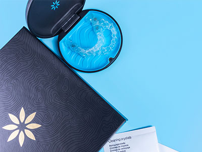 A blue toothbrush resting on a pamphlet with a logo, both placed against a blue background.