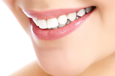 The image shows a close-up of a person smiling with their teeth, revealing a bright smile, and appears to be a product or service advertisement for dental care or cosmetic dentistry.