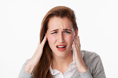 A woman with her hand on her ear, expressing concern or discomfort.