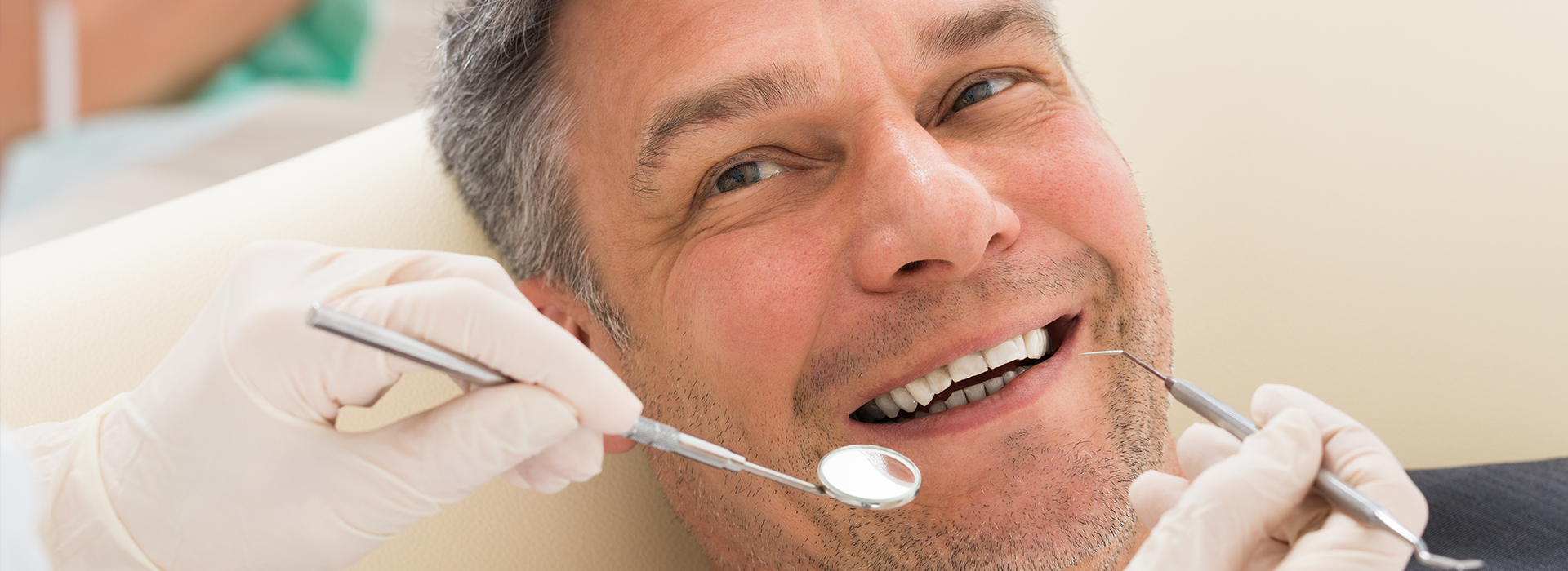 A man in a dental chair receiving oral care, with a dentist working on his teeth.