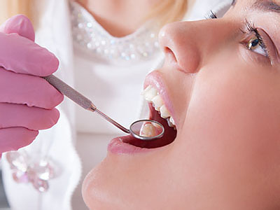 The image shows a close-up of a person receiving dental treatment, with a dental professional using a drill on the patient s teeth.