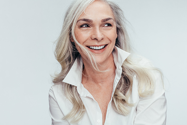 A woman with short hair, wearing a white blouse and smiling at the camera.