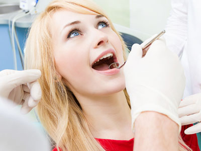 A woman in a dental chair receiving dental care with a smiling expression.