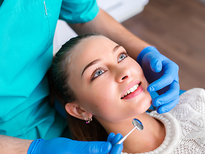 The image shows a dental professional performing a teeth cleaning procedure on a patient, with the patient s face in close-up focus.